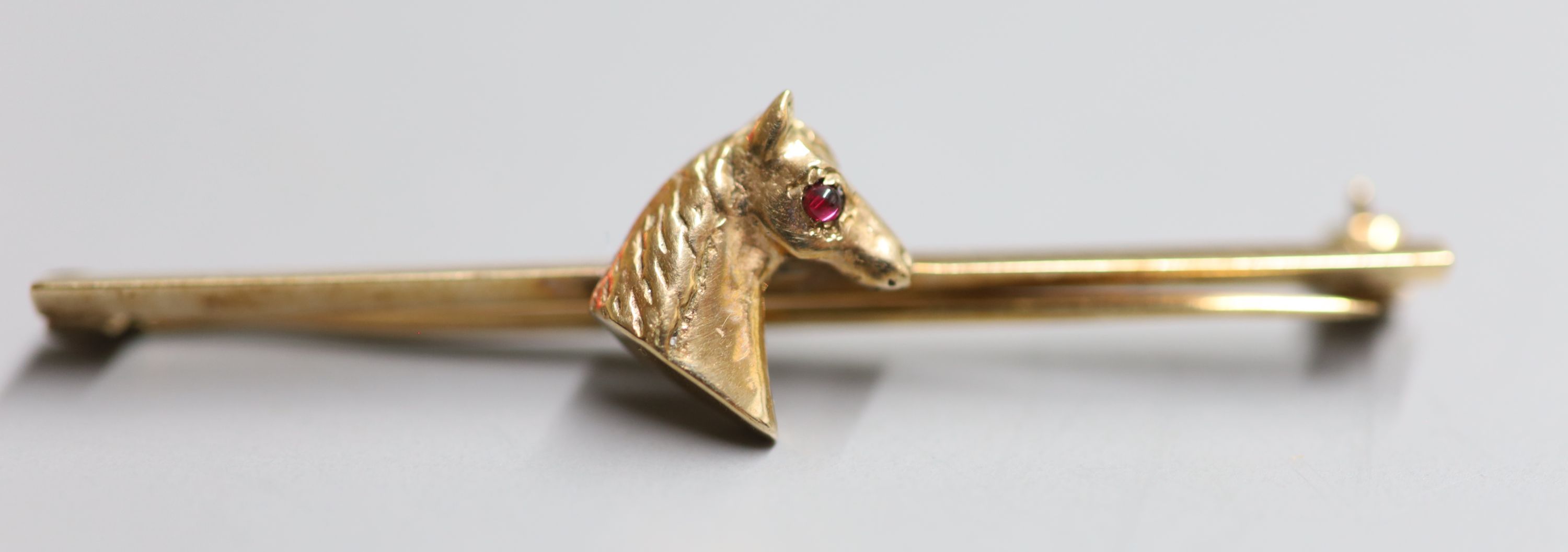 A yellow metal tiepin with horses head inset cabochon ruby eye, 50mm, gross 3.7 grams.